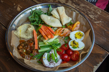 Israeli breakfast with boiled egg, Lahoh Yemeni flat bread, fresh vegetables, Israeli appetizers - hummus, labneh, tuna sauce, curd cheese and dried tomatoes served in Saint Petersburg, Russia