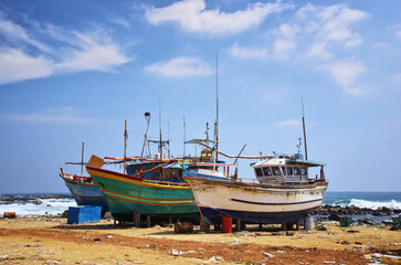 Fototapeta na wymiar Dondra port, Sri Lanka. Abandoned fishing boats on the shore. Dirty harbor and old ships.