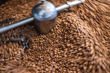 Best coffee background. Freshly roasted coffee beans in motion. Artistic hot beverage closeup concept. Coffee roaster cylinder roasting and mixing coffee beans
