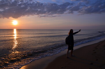 silhouette of person walking on the beach at sunset