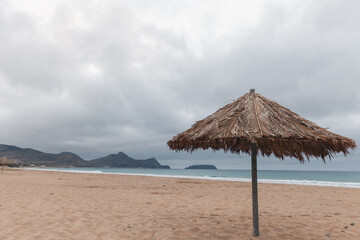 Wooden umbrella is on an empty beach