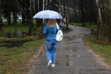 A girl with an umbrella walks through the park.
