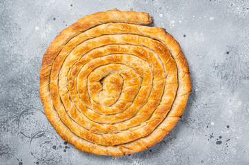 Fototapeta na wymiar Baked homemade traditional Greek cheese pie on kitchen table. Gray background. Top view