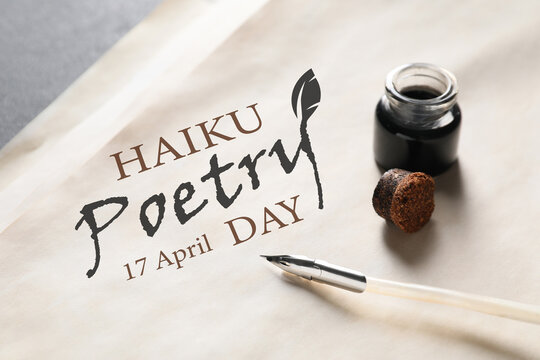 Paper sheet with text HAIKU POETRY DAY 17 APRIL and feather pen with inkwell on table, closeup
