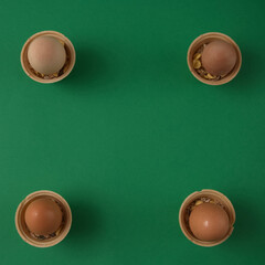 Fresh eggs are prepared for Easter in small ice cream cones with copy space on a green background. Minimalistic Eastern scene.