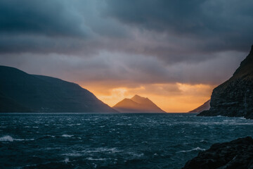 Rocky shore on a cloudy day. Cliffs of Kalsoy island. Early morning in Mikladalur, wild Faroe Islands. November 2021