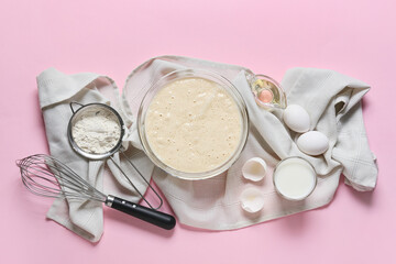 Raw batter with whisk and ingredients on color background