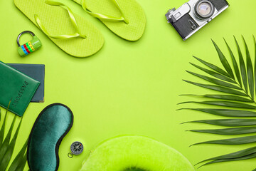 Frame made of travel items, documents and flip-flops on green background