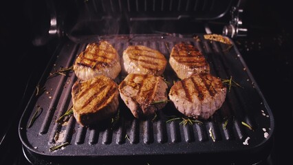 Delicious juicy meat steak cooking on grill. Aged prime rare roast grilling tenderloin fresh marble tenderness beef. Prime beef fry on electric roaster, rosemary, black pepper, salt. Slow motion.