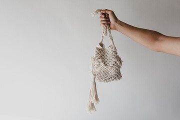 Hand holding handmade macrame on white background.