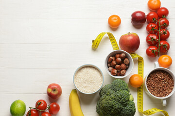 Different healthy products and measuring tape on light wooden background