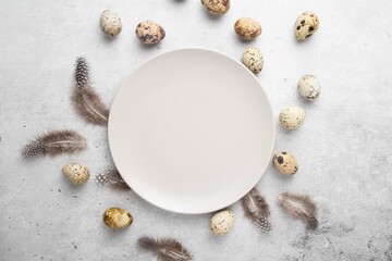 Fresh, farm quail eggs and feathers on light background. Protein diet. Healthy diet. Easter holiday greeting card. Top view, copy space or empty place for text.