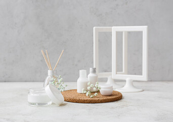 Composition with cosmetic products and flowers on light background