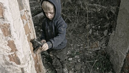 Child playing war in ruins 