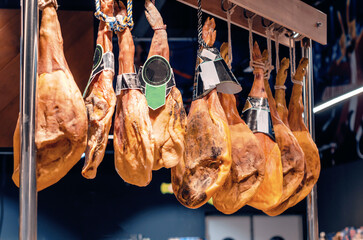 Jamon hangs on a crossbar in a supermarket. Blurred background.