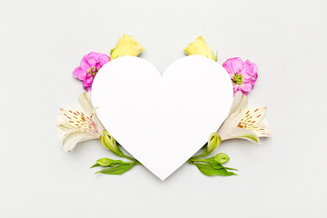 Composition with beautiful flowers and blank heart shaped card on white background