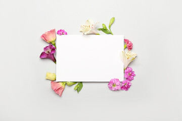 Frame made of different flowers and blank paper card on white background