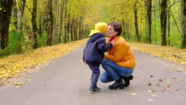 Little boy gives a bouquet of autumn leaves to his mother