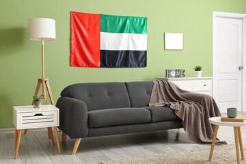 Interior of stylish living room with black sofa, UAE flag and green wall