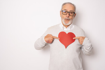 Happy senior man showing red paper heart isolated over white background. Health concept.
