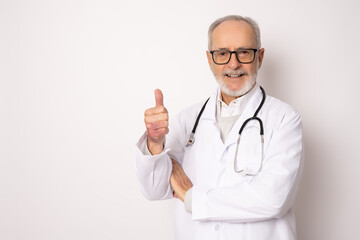 Senior grey-haired doctor man standing over isolated white background happy face smiling with thumb up looking at the camera. Positive person.