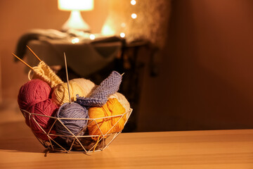 Basket with yarn and needles on table in room