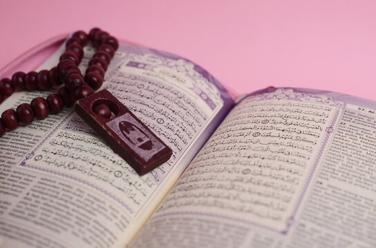 Muslim Quran and prayer beads on pink background