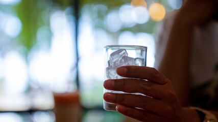 Woman hand holding ice in glass in the shop or restaurant