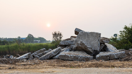 A close-up view of large concrete rubble piled up on the ground from a country road demolition.