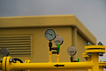 Rozdzielnia gazu ziemnego ( metan ) - żółte rury , strzałka , manometry ( ciśnieniomierz ) , zawory połączenia , żaluzje , rurociąg ( gazociąg ) .  - obrazy, fototapety, plakaty