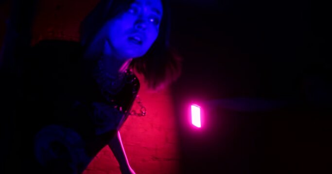 Slow motion low angle shot of frightened girl climbing up the stairs and running away from the pursuer. The witness of illegal fights is trying to hide in the dark corners of an underground club