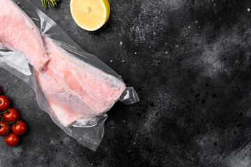 Orange roughy frozen pack fish meat, with herbs, on black dark stone table background, top view...