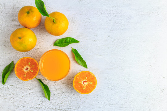 .Freshly squeezed orange juice in a glass and fresh citrus fruits on a white background. © NARONG