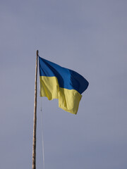 The flag of Ukraine hoisted in flagpole against blue sky
