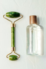 massage stone jade gouache scraper and facial roller with cosmetic cream.