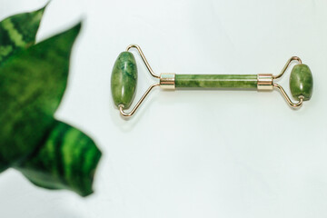 massage stone jade gouache scraper and facial roller light background.