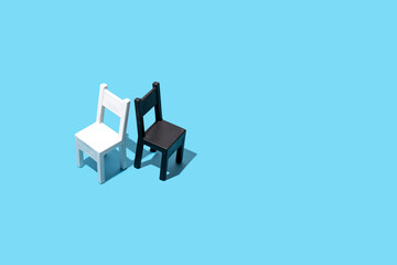 
Two chairs, black and white concept on a pastel blue background. Contrast, opposites, 