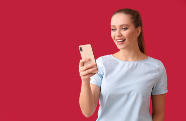 Pretty young woman with mobile phone on red background