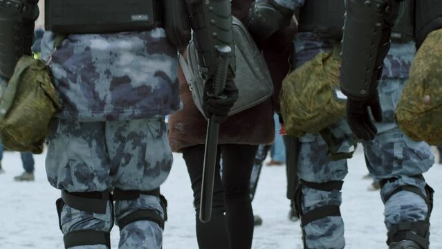 Russian riot police units in armored uniforms with enforce gear. Policeman officers walking with clubs, demonstrating authority and power. Holding, carrying billy batons by street anti-rally teams.