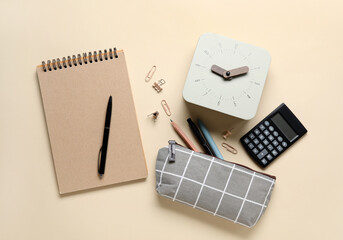 New alarm clock with pencil case and stationery on beige background