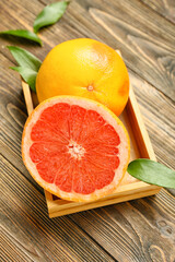 Box with delicious grapefruits on wooden background