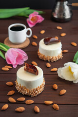Two cupcakes with chocolate white coffee cup almond and tulips on wooden table. Selective focus