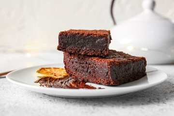 Plate with pieces of delicious chocolate brownie on light background