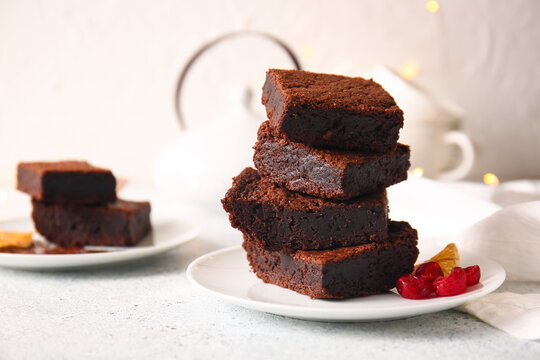 Plate with pieces of delicious chocolate brownie on light background