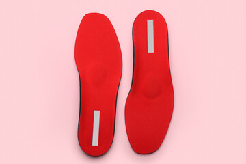 Pair of red orthopedic insoles on pink background
