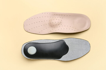 Pair of orthopedic insoles on color background
