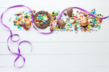Fototapeta na wymiar Composition with chocolate Easter eggs and different candies on light wooden background