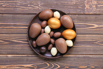 Plate with different chocolate Easter eggs on wooden background