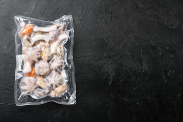 Raw seafood, mussels, squid octopus in vacuum pack, on black dark stone table background, top view...
