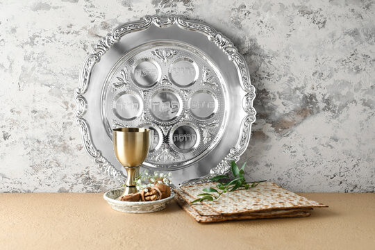 Passover Seder plate with cup of wine, walnuts and matza on table against grunge background